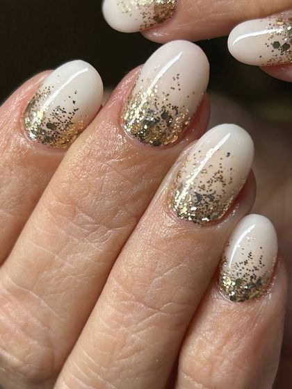 A festive and glamorous gold glitter ombré. The dense gold glitter at the tips fades beautifully into the milky white base, perfect for a celebration.