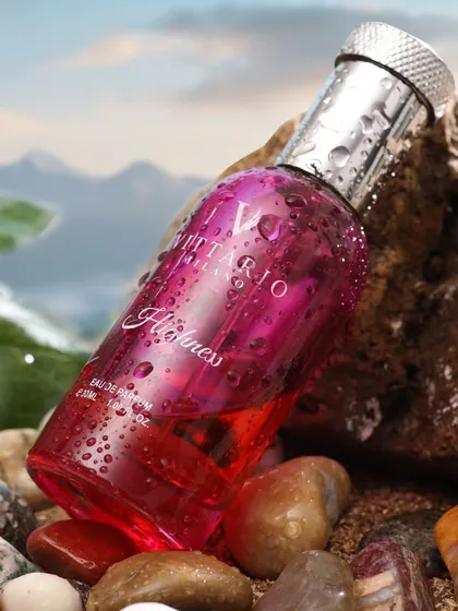 A close-up of a pink perfume bottle resting on rocks, with water droplets suggesting freshness. This detailed shot is perfect for highlighting the product's design and evoking a sensory experience.
