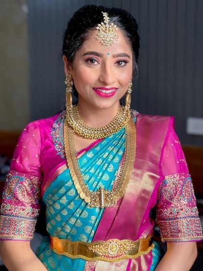 This bride is a vision in our designer silk saree, featuring a vibrant combination of blue and pink. Her joy and radiance are what make my work so fulfilling.