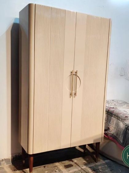 This tall, slender cabinet features a beautiful ribbed texture and unique circular brass handles. It's a sophisticated storage piece that adds a touch of art deco elegance to any room.