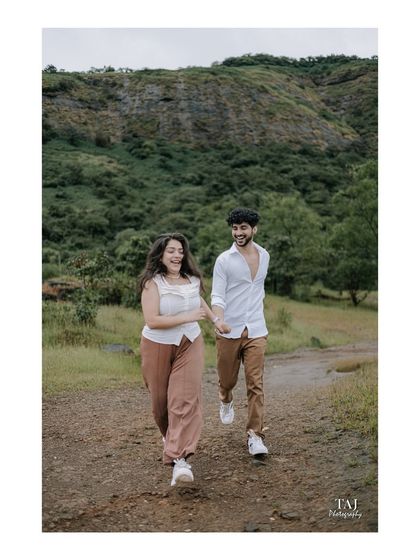 A happy, dynamic shot of the couple walking hand-in-hand on a rustic path. Her joyful expression and their connected hands tell a story of a happy journey together.