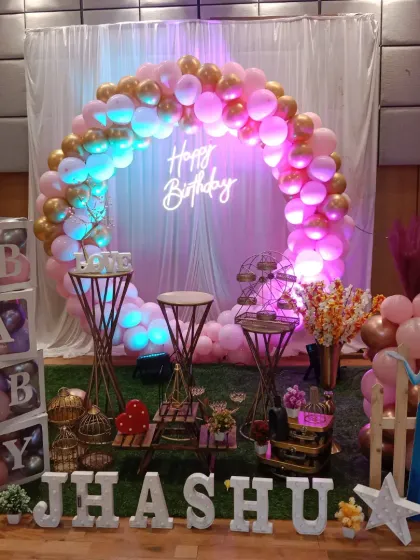 A beautiful Frozen-themed birthday party with a pink and gold balloon ring. The setup includes Elsa cutouts and "BABY" blocks for a first birthday.