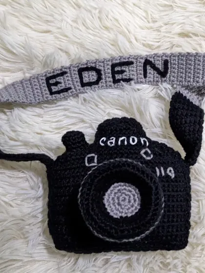 Another view of the personalized crochet camera pouch, showing the name on the strap.