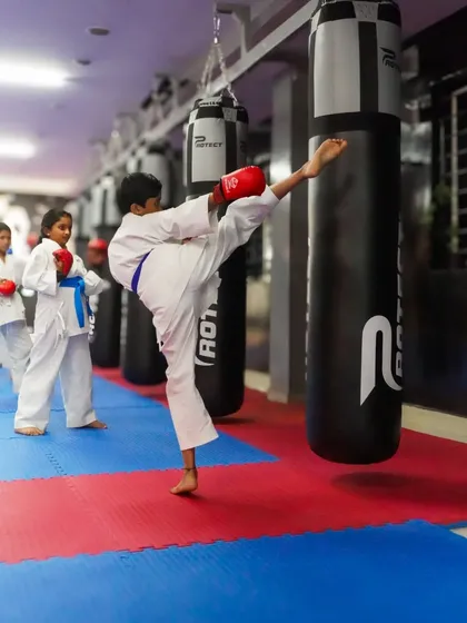 Power and precision in a single motion. A young student practices a powerful kick on the heavy bag, demonstrating the technique and strength we cultivate in our karate classes. This is a core part of building a strong martial artist.