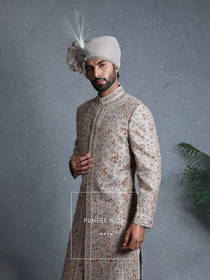 A closer look at the coffee beige sherwani, highlighting the three-dimensional floral artistry and threads that carry culture. This is a garment of grace and grandeur.