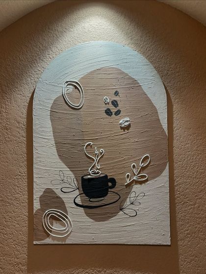 The finished coffee-themed artwork installed in its niche at the cafe. The spotlight highlights the textures and makes the piece stand out.