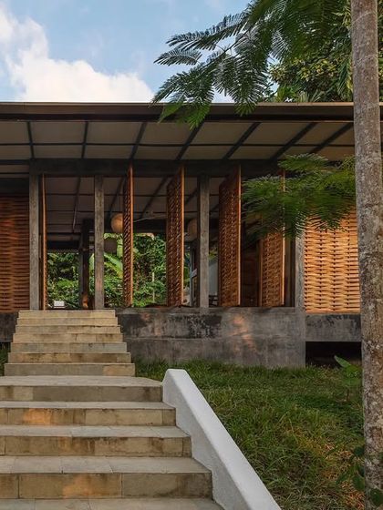 The entrance to the private villa, showcasing the woven teak wood panels that provide both privacy and natural ventilation. This handcrafted facade is a key element of the villa's eco-friendly and climate-responsive design.