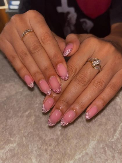 A classic glitter French manicure on almond-shaped nails with a sheer pink base.