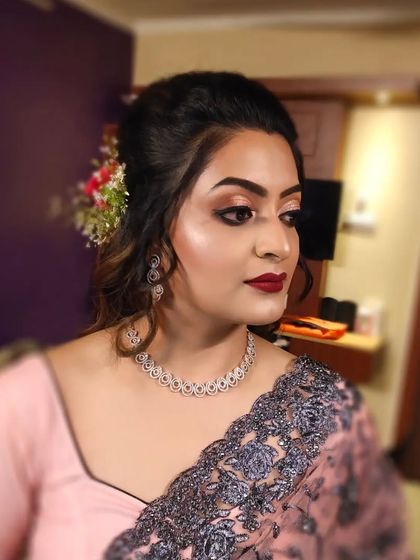 An elegant party look for a client in a pink saree. The makeup is sophisticated with a bold red lip.