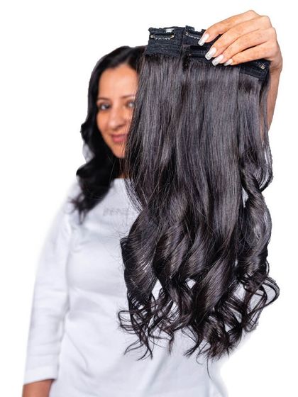 A model holding up a set of our wavy clip-in extensions. You can see the quality and natural curl pattern that will blend beautifully with your own hair.