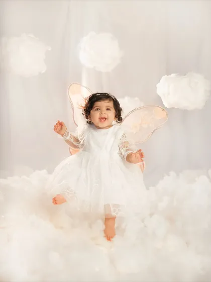 A little angel dancing on clouds for her first birthday. This is from my 'Journey to One Year' series, where I design magical studio setups like this dreamy cloud theme to celebrate your baby's biggest milestones.