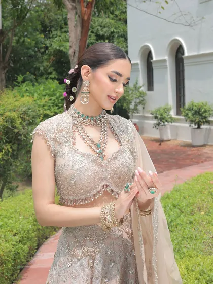 A candid moment showing the bride's serene expression, complemented by the soft tones of her outfit and the natural garden setting.