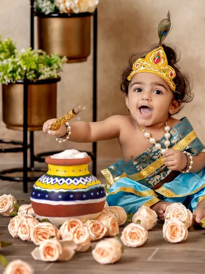 An action shot of our little Krishna, excitedly playing with his butter pot and surrounded by a bed of roses.