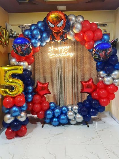 A full circular balloon arch for a 5th birthday, designed with a Spider-Man theme. The red, blue, and silver balloons, along with character accents, create an exciting photo backdrop.