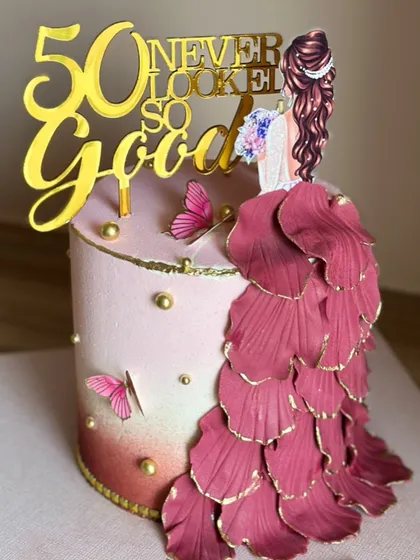 Celebrating a milestone like 50 deserves a cake that’s as fabulous as the person it's for. This design features an elegant flowing gown made of delicate, hand-shaped petals, blush tones, and gold accents, proving that 50 never looked so good.