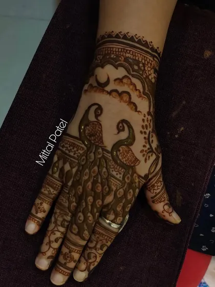 A single hand adorned with a beautiful peacock design. The details in the feathers and the surrounding floral elements make this a standout piece.