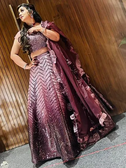 The ruffled dupatta adds a playful and modern element to this sequined lehenga, making it a fun and fashionable choice for any festive event.
