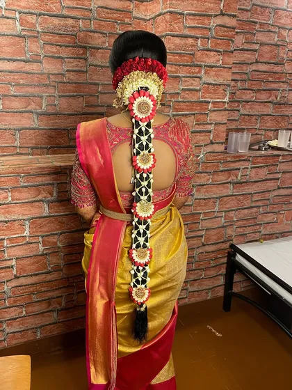 This is a beautiful floral braid for a Muhurtham. I used jasmine and red flowers to create a pattern along the plait, which looks stunning against the bride's gold and red saree.