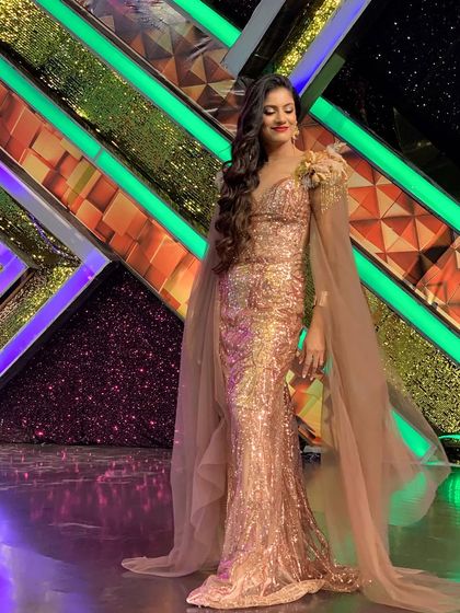 Another angle of the elegant caped gown, showcasing its flow and design on the brightly lit stage of the dance show.