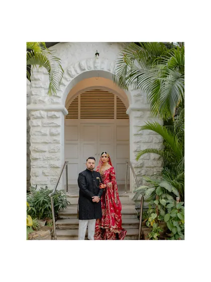 A picture of perfect partnership. The couple stands together, framed by a beautiful archway and lush greenery, creating a classic and elegant wedding portrait that symbolizes their new beginning.