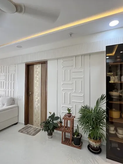 Another angle of the contemporary living room, highlighting the clean lines of the sofa and the natural touch of indoor plants against the white textured wall.