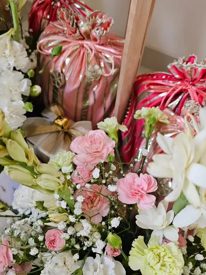 Wedding season keeps me surrounded by gorgeous blooms. This close-up shows the beautiful texture of gota-detailed potlis nestled among fresh white and pink flowers, a classic combination for wedding hampers.