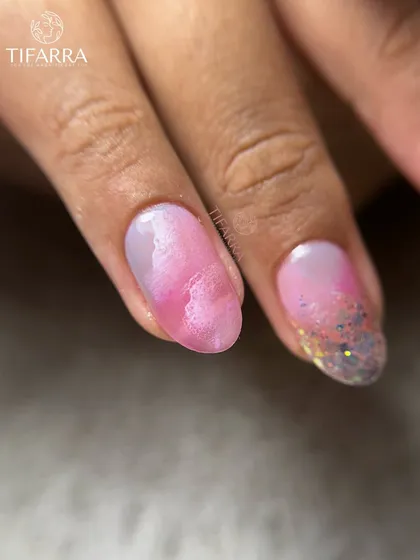 Cotton-candy dreams with a touch of sparkle. A close-up of a nail with a pink watercolor effect and a glittery tip.