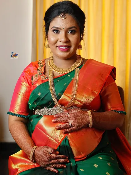 A seated portrait of a mother-to-be, showcasing her traditional jewelry and the intricate details of her saree during her baby shower.