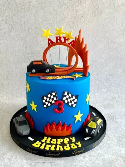 A Hot Wheels-themed cake for a 3rd birthday. The design includes the iconic orange track loop and flames for a fast and fun look.