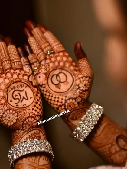 A closer look at the engagement mehendi stain, showing the initials and ring motifs in beautiful, dark color.