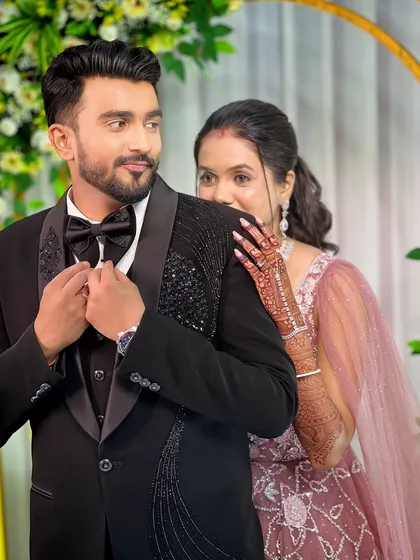 The couple looking glamorous for their reception. The groom's look is classic and sharp in a black tuxedo.