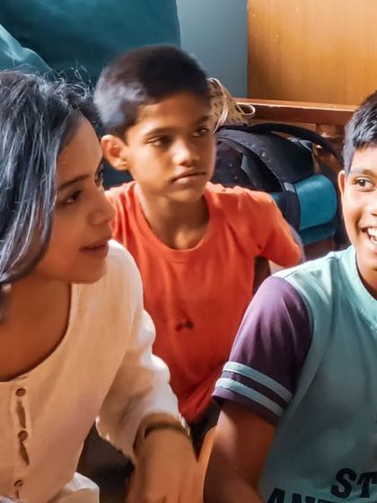 An intimate moment of connection between a volunteer and children. These interactions are where the magic happens, building trust and making each child feel seen and heard.