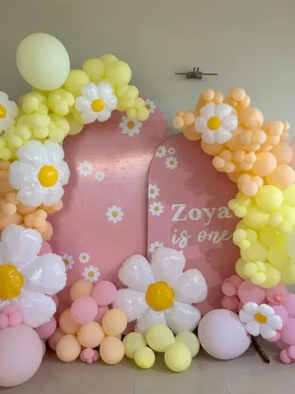 A closer view of the daisy-themed first birthday setup, highlighting the custom backdrop and the arrangement of daisy-shaped balloons.