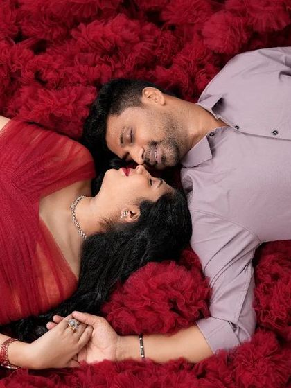 An intimate top-down shot of a couple on a bed of red ruffles. Their close embrace and serene expressions capture the deep love and connection of this special time.