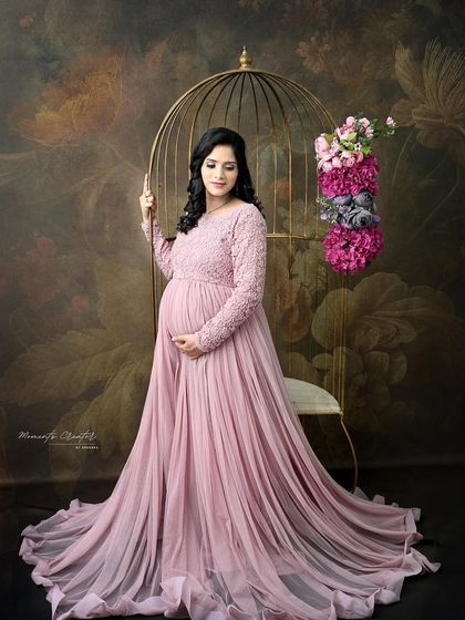 A graceful portrait in a dusty pink gown. Posed next to the golden birdcage against a floral backdrop, this image is the epitome of romantic elegance.