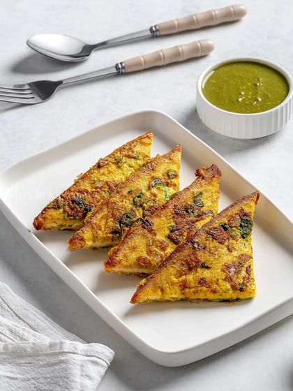 A masala omelette cut into triangles, served with a side of green chutney.