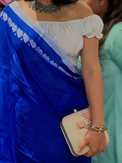 A close up on the details. This shot highlights how the delicate lines of the artwork on my clutch contrast beautifully with the bold blue of the saree and the intricate design of the oxidized jewelry.
