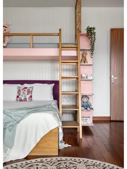 This daughter's room in 'Vasudhalayah' is equipped with custom bunk beds in a soft pink finish. The design includes an integrated ladder that doubles as a bookshelf.
