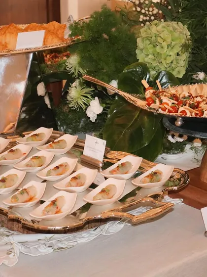 A wide shot of one of our elegant green and white themed grazing tables, showcasing the variety of appetizers and the beautiful floral arrangements.
