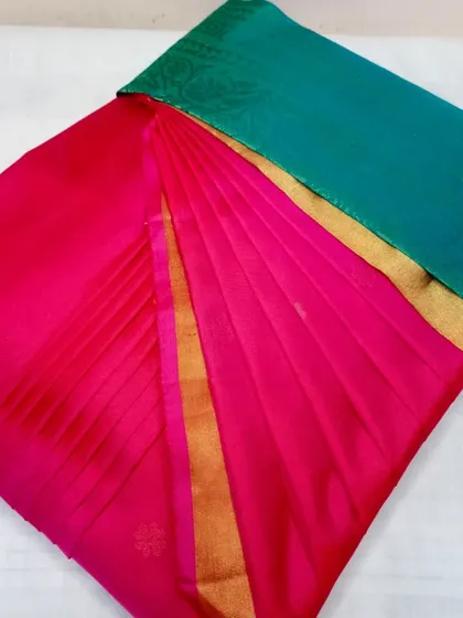 A pink and teal silk saree, pleated and ready to be worn.