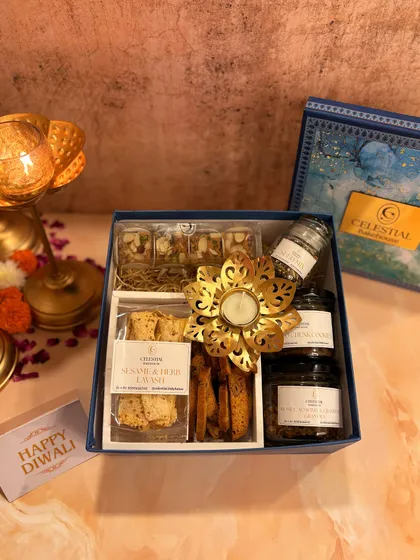 The 'Illuminating Indulgence' Diwali hamper includes whole wheat almond biscotti, rose and pistachio shortbread, and jars of our granola and cookies, complete with a metallic flower diya.