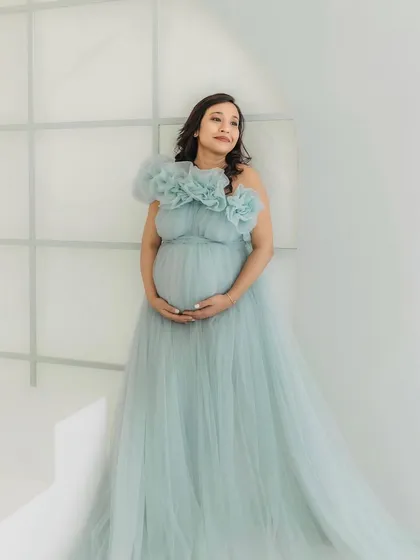 A serene portrait in a minimalist studio setting. The soft ice blue color and flowing tulle of the gown create a peaceful and elegant atmosphere.