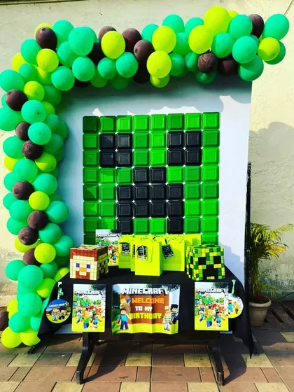 A creative Minecraft-themed party setup. We built a Creeper face backdrop using green and black elements and included game-themed gift bags and props to bring the popular video game to life.