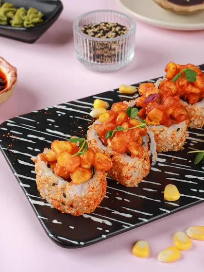 Spicy corn sushi on a modern, black-and-white striped plate. The vibrant colours and interesting textures make this a very eye-catching and contemporary sushi shot.