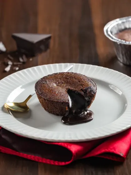 A classic choco-lava cake on a white plate, cut open to reveal the gooey, melted chocolate inside.