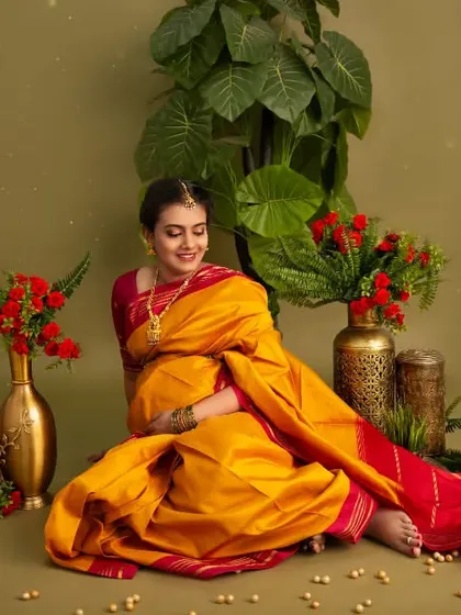Seated gracefully amidst plants and flowers, this portrait in a yellow silk saree is full of warmth and natural beauty, celebrating the life-giving energy of motherhood.