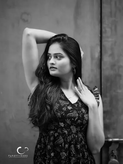 An elegant and poised black and white portrait. The lighting is soft, and her expression is calm and confident, creating a timeless beauty shot.