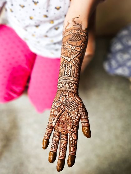 A single arm shot highlighting the majestic peacock motif at the top of the design.