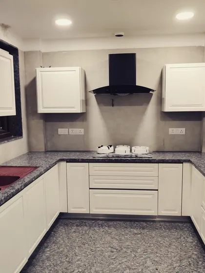 Here is a finished kitchen from a large 600 sq. yd. project in DLF Phase V, Gurgaon. It features classic white shaker-style cabinets, a durable granite countertop, and a functional U-shaped layout designed for heavy daily use.