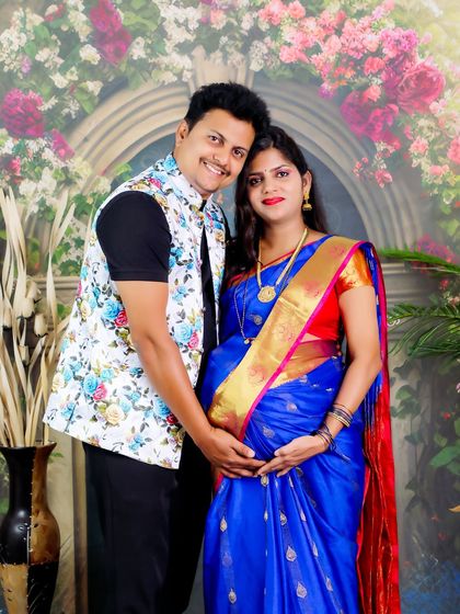 A happy couple portrait celebrating their pregnancy journey. The combination of a traditional saree and a modern floral vest creates a unique and personal look.